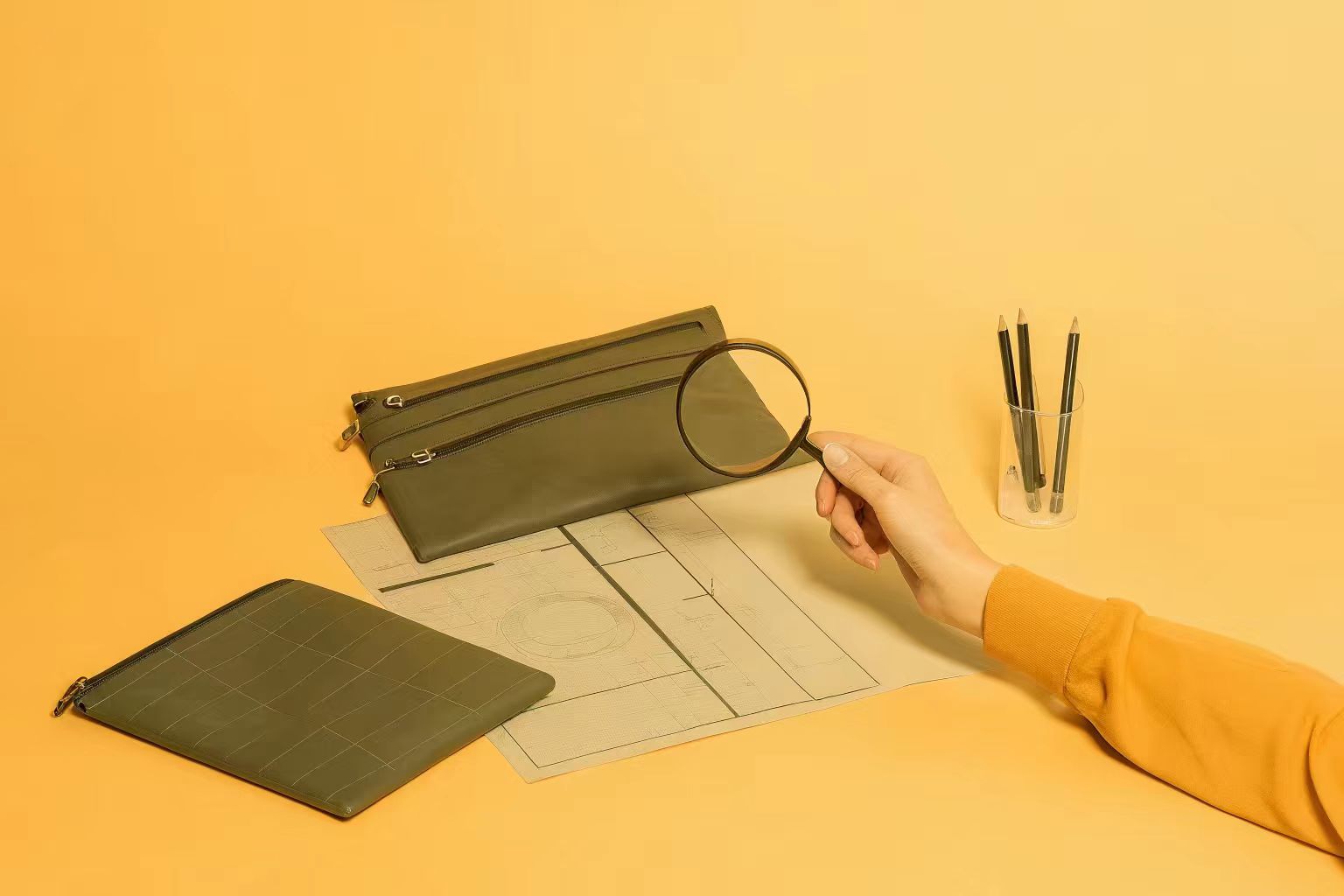 A designer carefully examining a physical pre-production sample of a makeup bag against her technical drawings